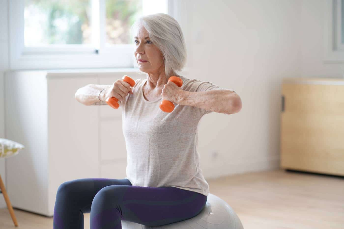 Attractive elderly woman exercising at home with swiss ball AdobeStock 229776928 - Don Du Souffle